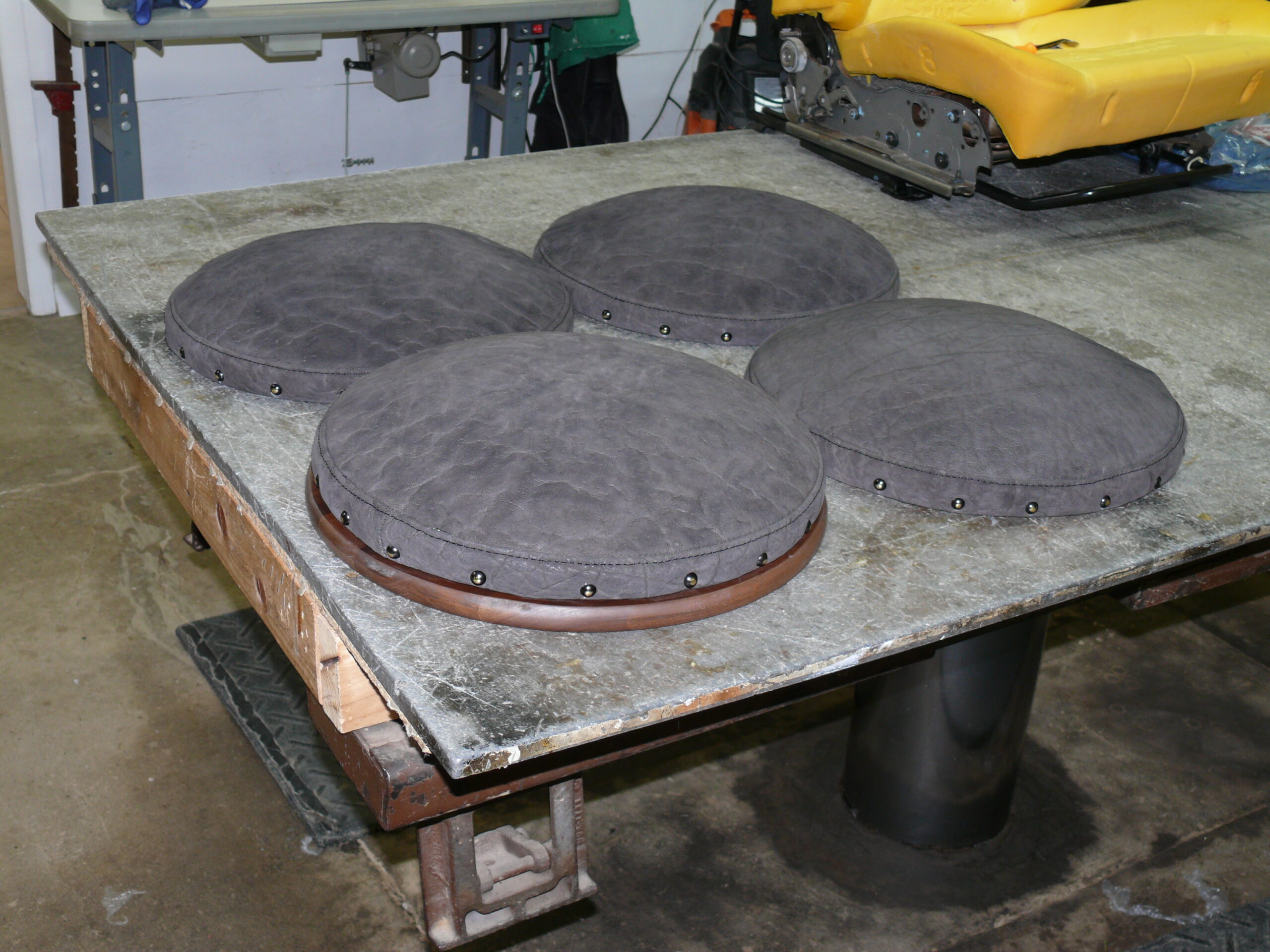 Exotic leather upholstery Pittsburgh PA: four round elephant hide stool seats in gray with brass nailhead trim at Alex Upholstery Shop