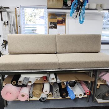 Custom-made cushions for RV featuring neutral textured fabric and professional boxed-edge tailoring on a workshop table