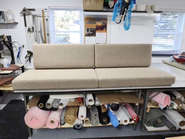 Custom-made cushions for RV featuring neutral textured fabric and professional boxed-edge tailoring on a workshop table