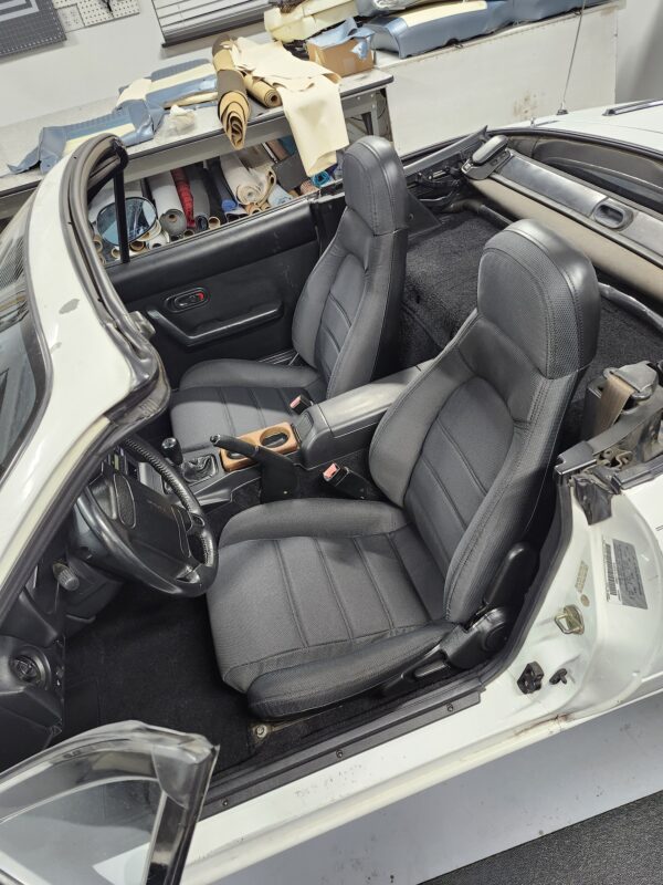 Reupholstery seat and change carpet for Mazda Miata 1990 featuring black fabric bucket seats and fresh black carpeting in a white convertible NA Miata