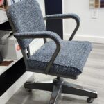 Vintage desk chair reupholstery featuring a mid-century metal swivel chair with blue and grey tweed fabric in a professional upholstery shop