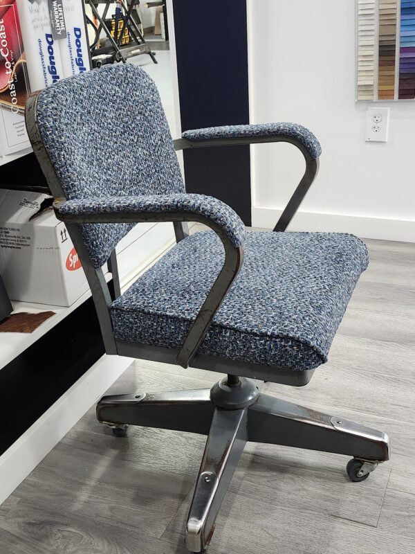 Vintage desk chair reupholstery featuring a mid-century metal swivel chair with blue and grey tweed fabric in a professional upholstery shop