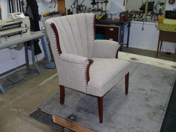 Mid-60s channel back chair featuring light grey textured fabric with precision vertical channels and decorative nailhead trim