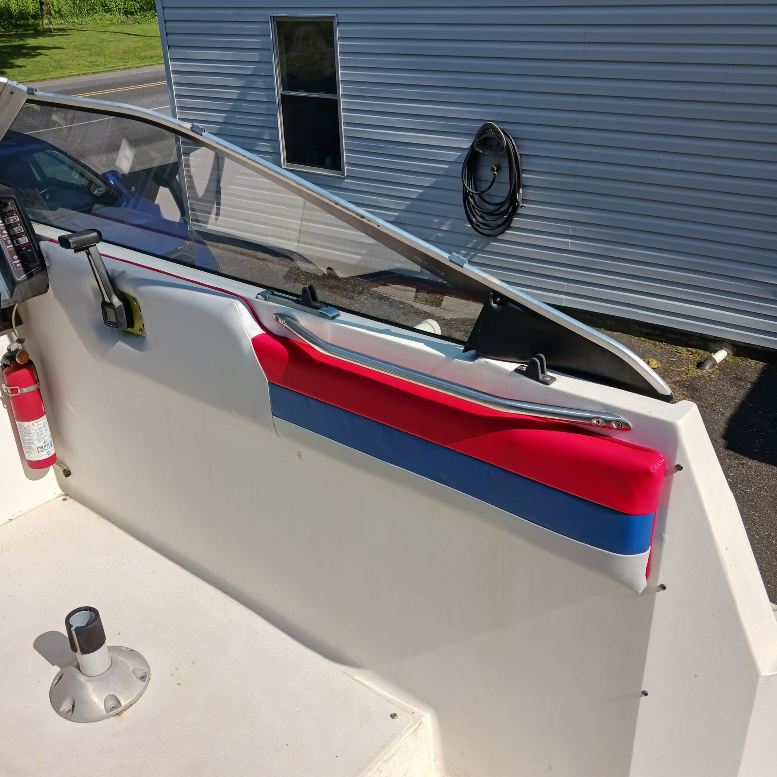Finished boat cockpit side panel with red and blue accent bands and chrome grab rail under the windshield