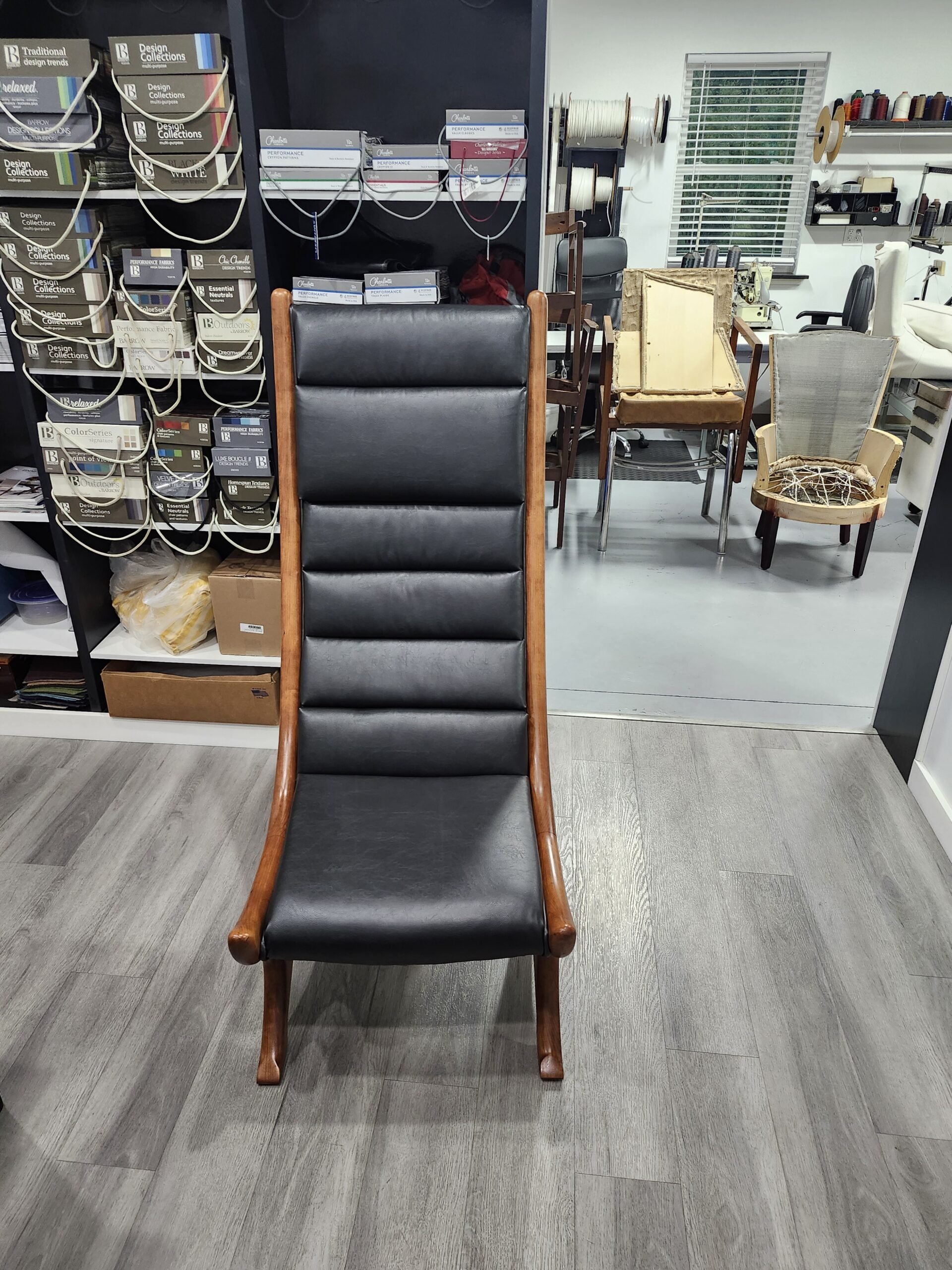 Finished sculptural high-back chair in channeled black top-grain leather, front view with exposed bentwood rails