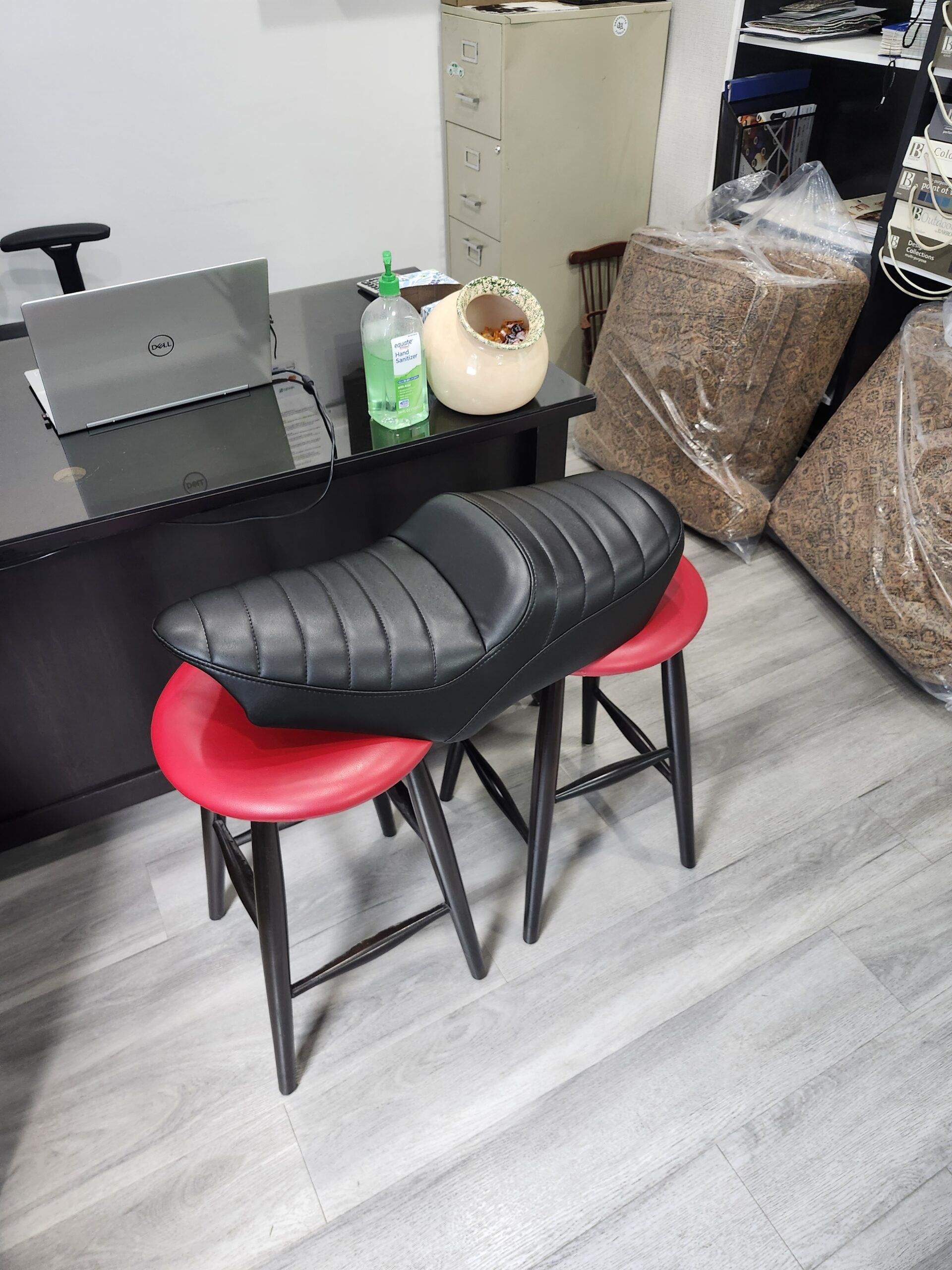 Side angle of the finished black vinyl motorcycle seat showing the tapered nose, pleated top and clean welted edge