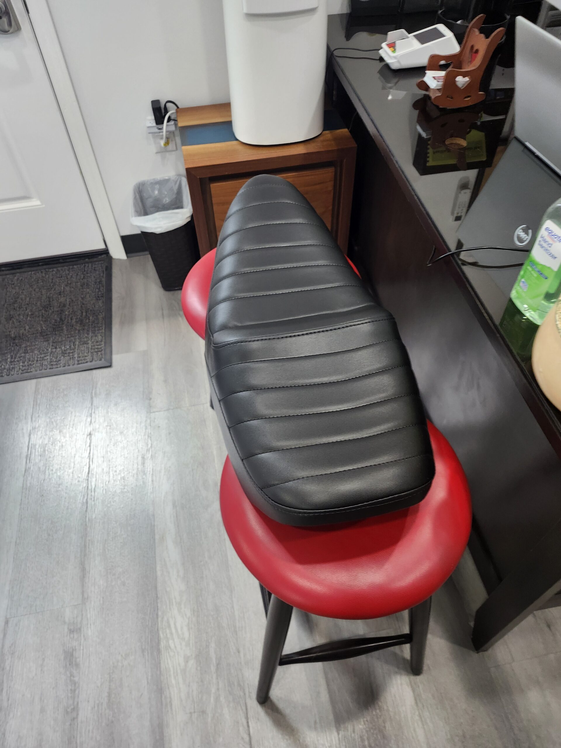 Overhead view of the black vinyl motorcycle seat showing evenly spaced horizontal tuck and roll pleats down the length of the saddle