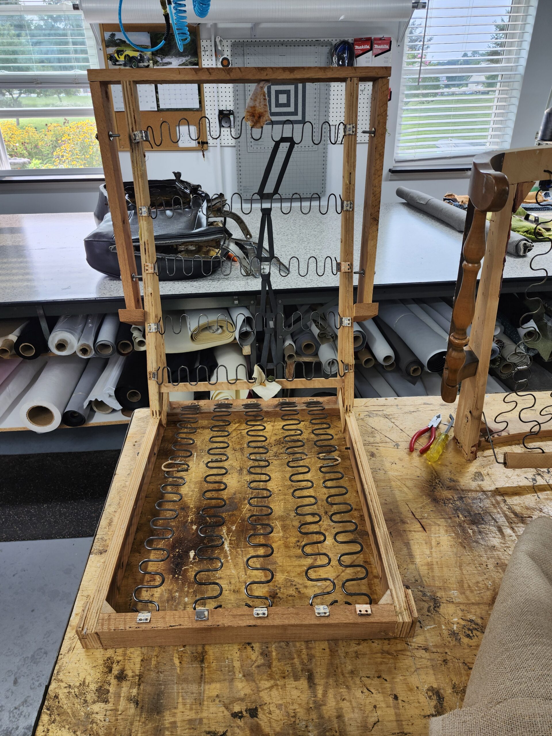 Recliner back frame and seat deck stripped to bare wood with new sinuous springs clipped in place on the workbench at Alex Upholstery Shop