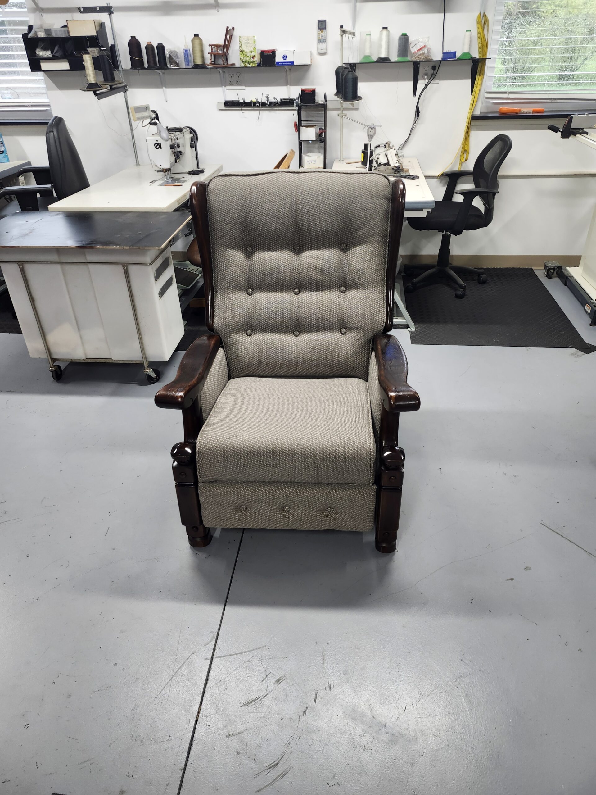 Wing recliner fully reupholstered in taupe tweed with button tufted back and refinished dark wood arms, front view in the Alex Upholstery Shop sewing room
