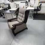Three quarter view of the reupholstered wood arm wing recliner showing the tufted back crown and curved wings
