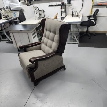 Three quarter view of the reupholstered wood arm wing recliner showing the tufted back crown and curved wings