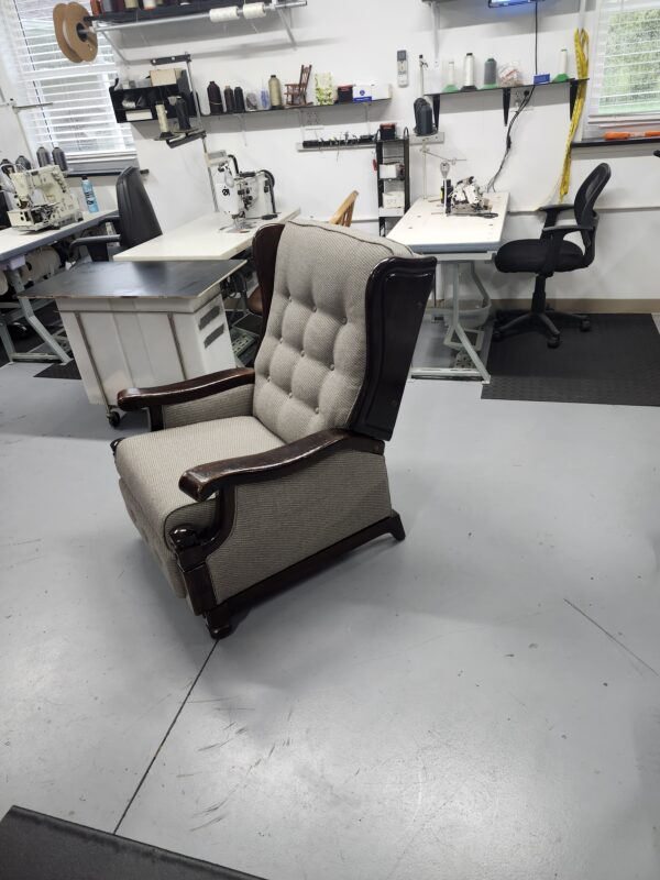 Three quarter view of the reupholstered wood arm wing recliner showing the tufted back crown and curved wings