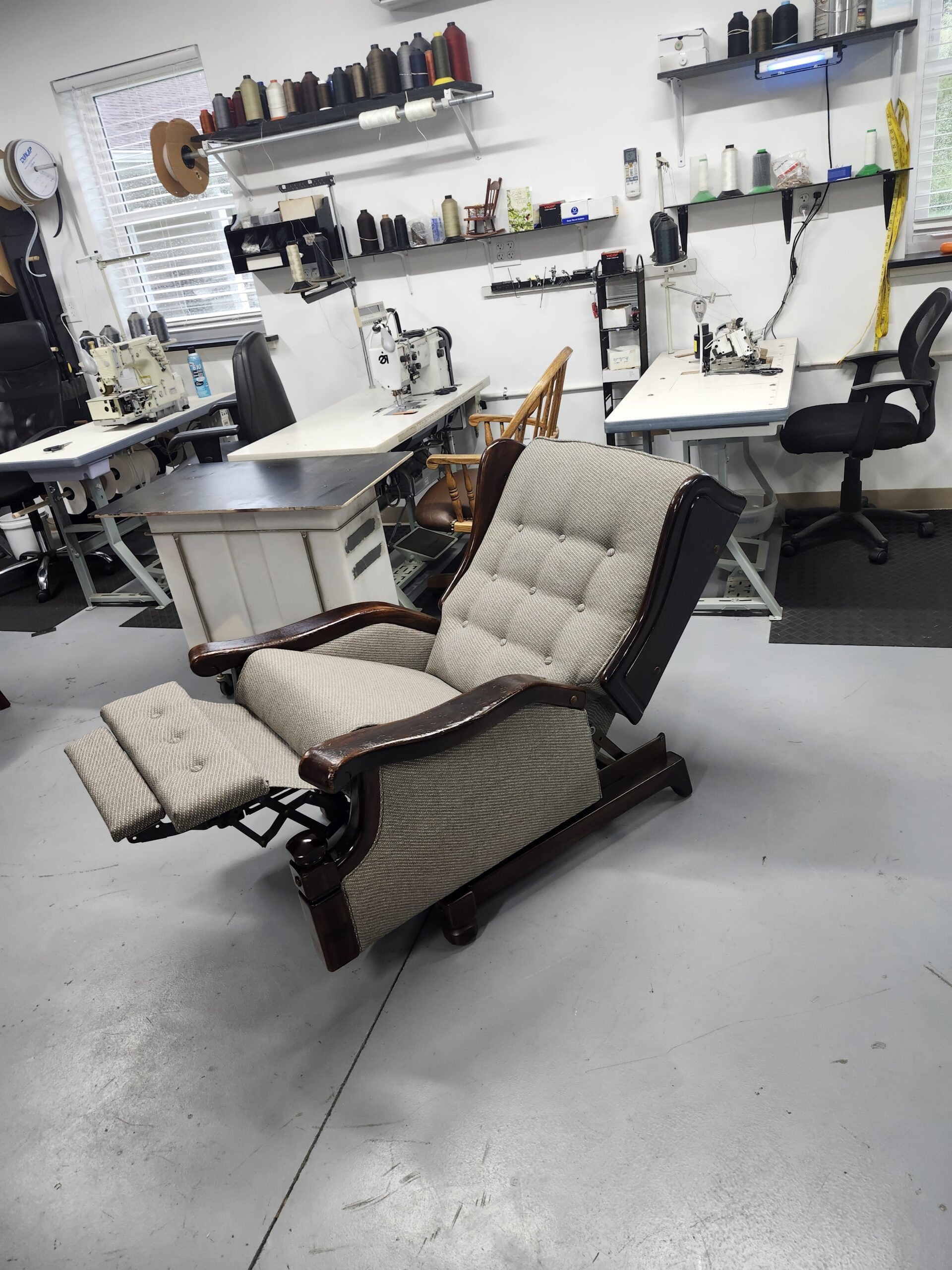 The reupholstered wing recliner fully reclined with the tufted footrest extended, showing the working wall away mechanism