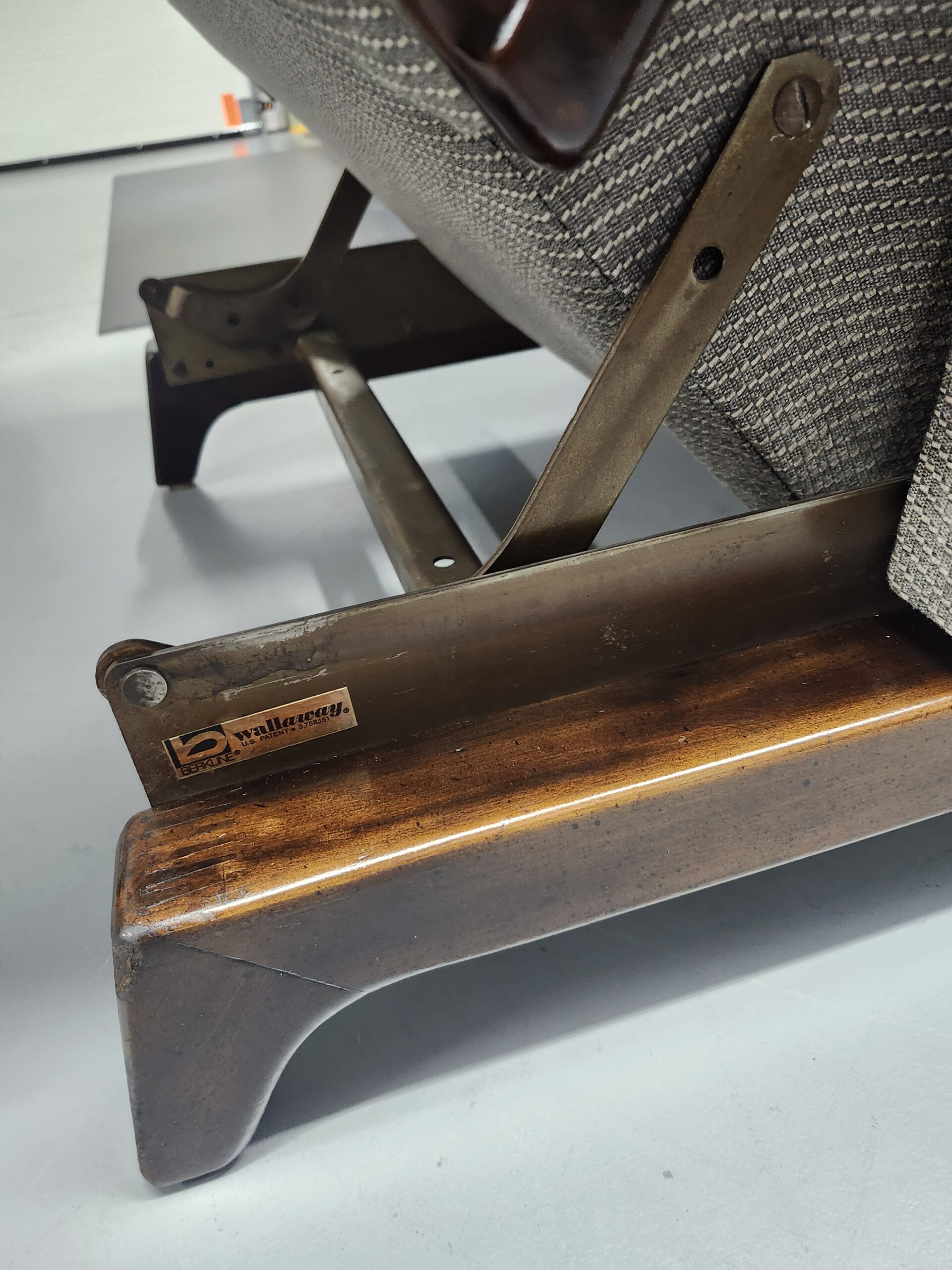 Close up of the Berkline Wallaway patent tag on the steel recliner linkage next to the refinished wood base rail
