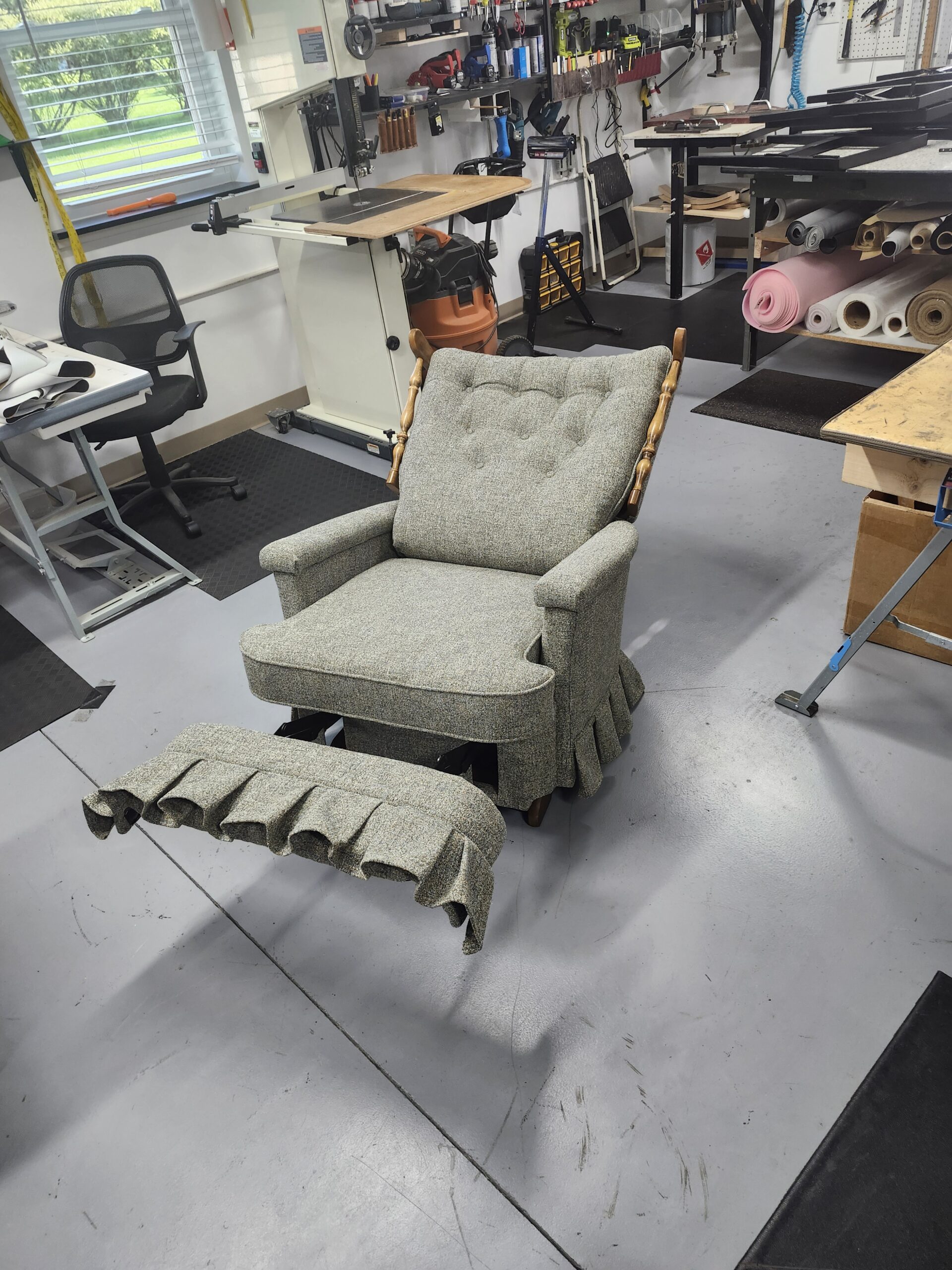 The rebuilt La-Z-Boy recliner reclined with the footrest extended and its own matching pleated tweed skirt flap, the original steel mechanism working
