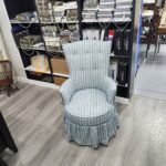 Chair reupholstery Lititz PA project: mid-century round slipper chair reupholstered in a light blue and white dotted stripe fabric with a five button tufted back, round welted seat and gathered skirt, in the Alex Upholstery Shop fabric showroom