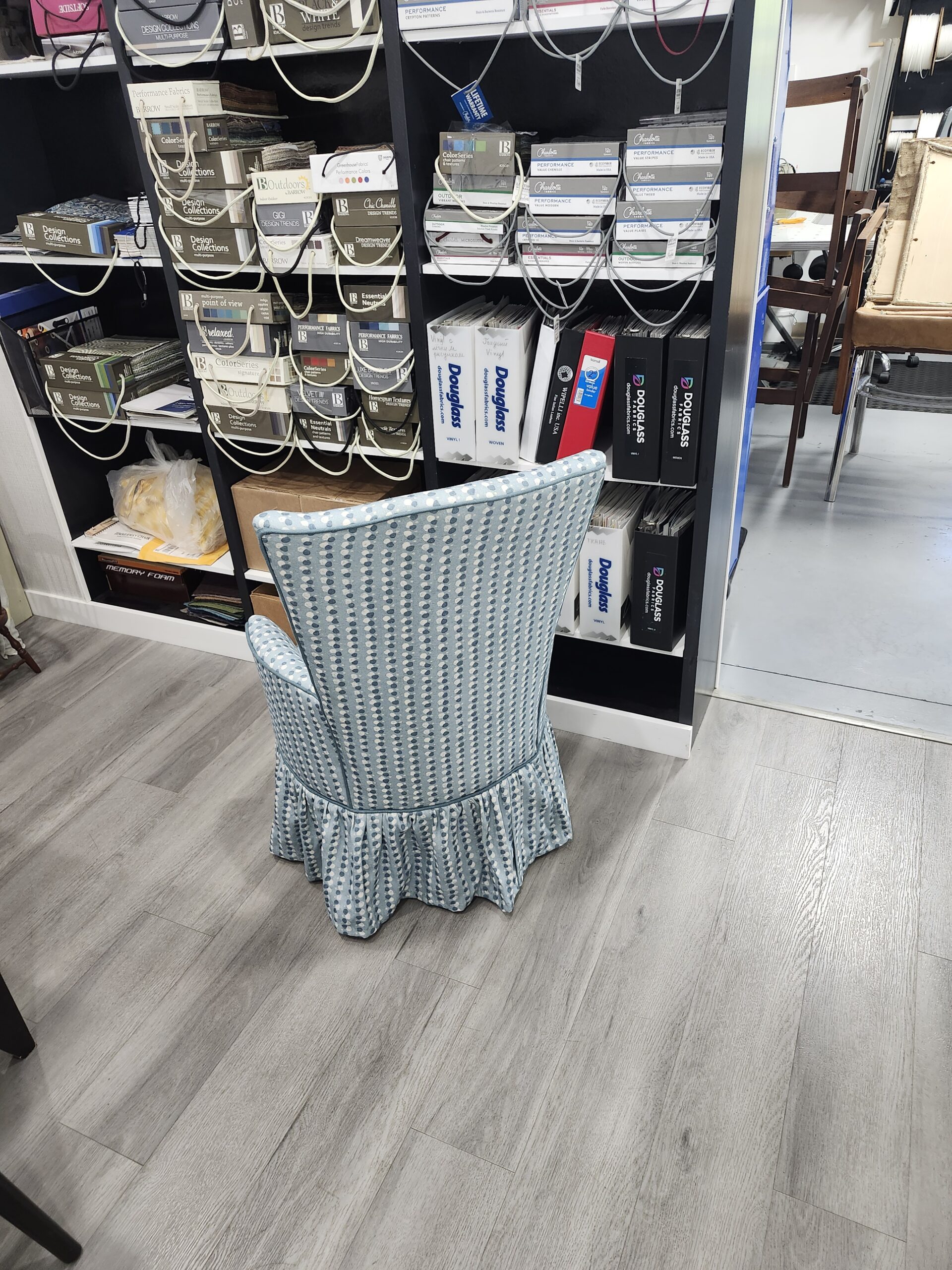 Rear view of the finished round slipper chair with the blue and white dotted stripes running straight down the outside back, around the piped edge and through the gathered skirt